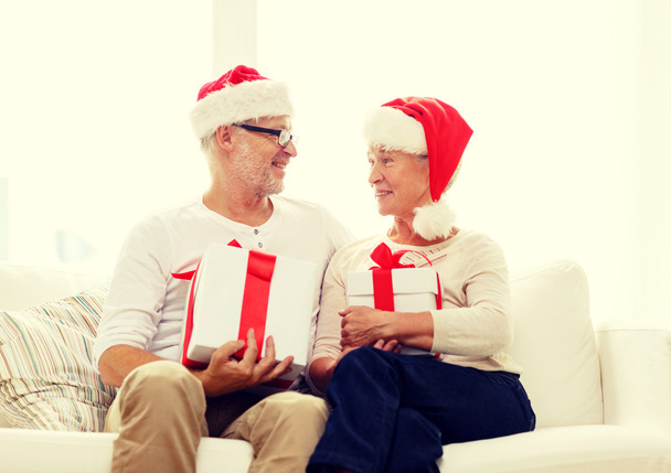 happy senior couple in santa hats with gift boxes - Фото, изображение