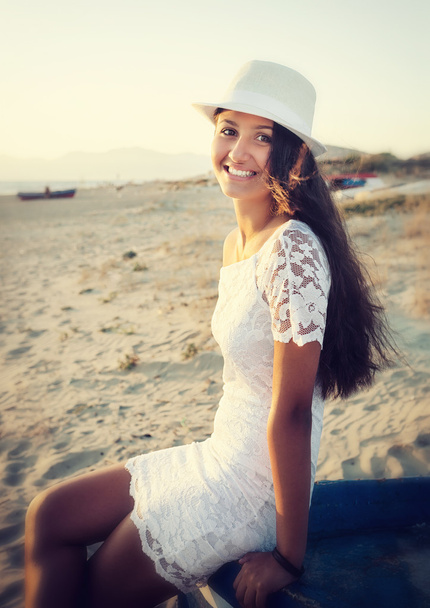 Kaunis nuori teini, jolla on valkoinen mekko rannalla auringossa
 - Valokuva, kuva