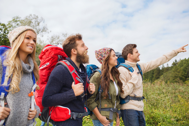 group of smiling friends with backpacks hiking - Фото, изображение