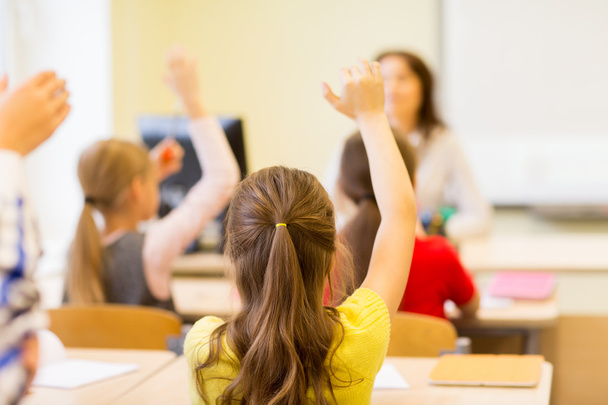 group of school kids raising hands in classroom - Zdjęcie, obraz