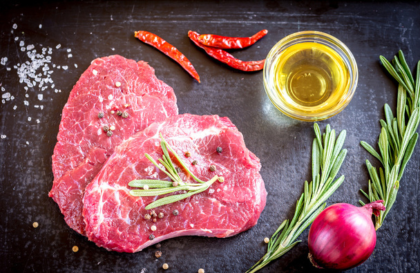 Steaks de bœuf frais avec des ingrédients sur le fond sombre
 - Photo, image