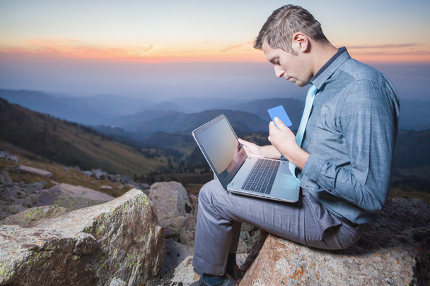 successful businessman on top of mountain, using a laptop - Foto, Bild