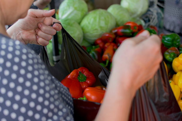 Красный перец в мешке - женщина покупает овощи на рынке
 - Фото, изображение