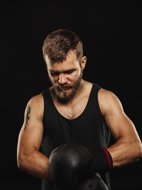Athletic bearded boxer with gloves on a dark background - Фото, изображение