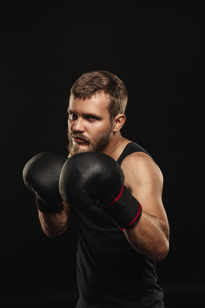 Athletic bearded boxer with gloves on a dark background - Foto, Imagen