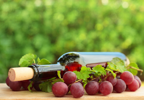 Винна пляшка, червоний виноград і зелене листя фон
 - Фото, зображення