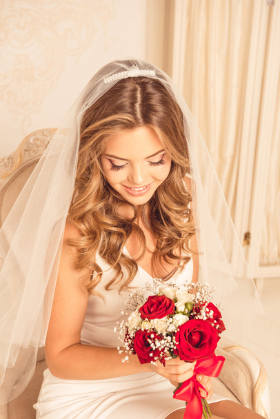 Красивая и счастливая невеста сидит со свадебным букетом
 - Фото, изображение
