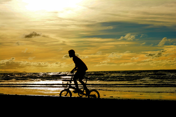 Gyermek kerékpár sziluett, a homokos strand. - Fotó, kép