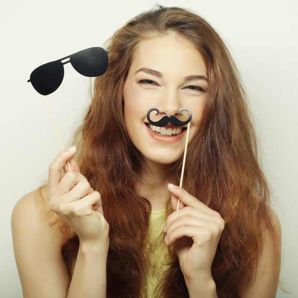 Attractive playful young woman holding mustache and glasses on a - Photo, image