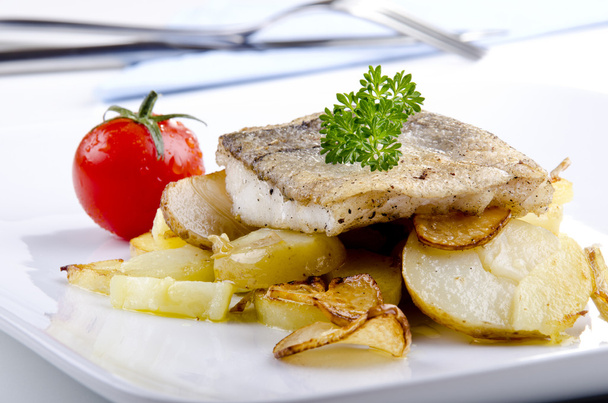 Haddock fillet on a plate with grilled potato and garlic - Photo, Image