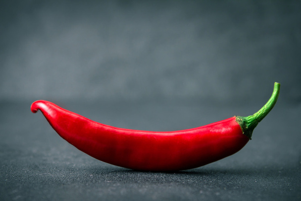 Chili pepper na černém pozadí kamene, usmíval se tvar - Fotografie, Obrázek