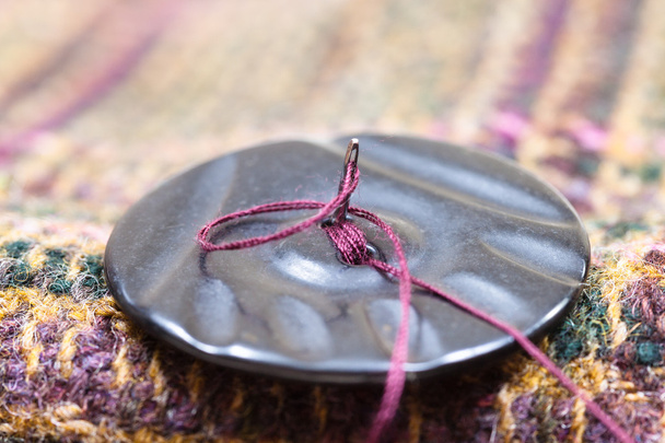 fixação de botão ao pano de lã por agulha
 - Foto, Imagem