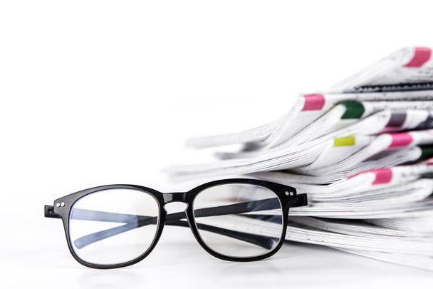 επιλεκτική εστίαση στην ανάγνωση γυαλιά με το στοίβαγμα των εφημερίδων - Φωτογραφία, εικόνα