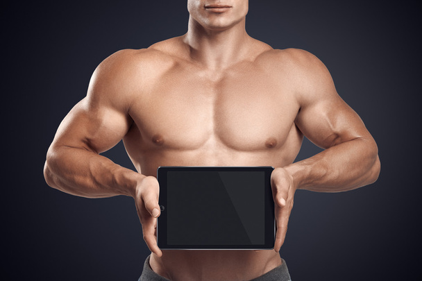 Fitness male holding horizontally digital tablet with blank scre - Foto, afbeelding