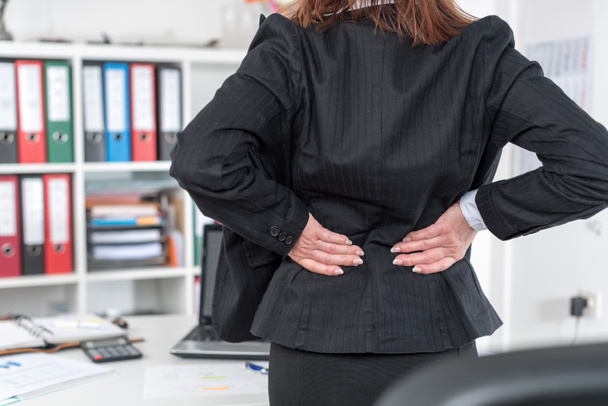 Mujer de negocios que sufre de dolor de espalda
 - Foto, Imagen