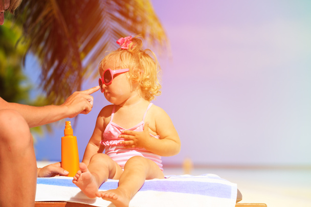 Eltern cremen Tochter mit Sonnencreme ein - Foto, Bild
