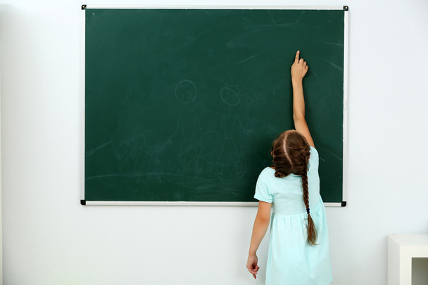Little girl pointing at something at chalkboard - Foto, Imagen
