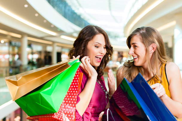 Δύο κορίτσια ψώνια σε εμπορικό κέντρο ψάχνει σε σακούλες - Φωτογραφία, εικόνα