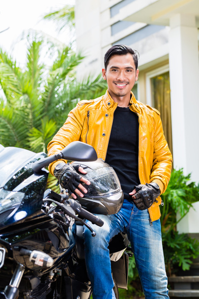 Aasialainen nuori mies ja hänen moottoripyörä tai skootteri
 - Valokuva, kuva