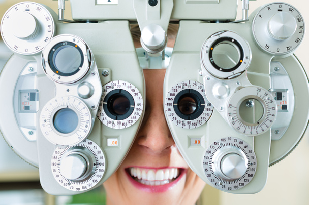 Młoda kobieta w phoropter za badanie wzroku - Zdjęcie, obraz