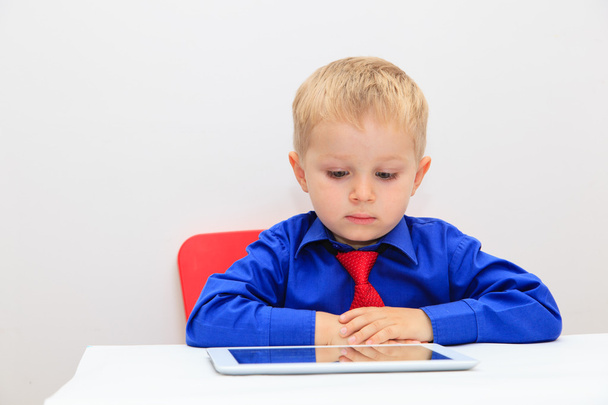 Kleiner Junge mit Krawatte und Blick auf Touchpad - Foto, Bild