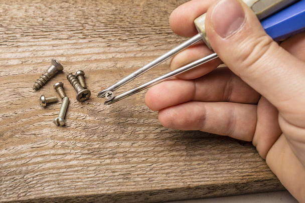 hands holding screws using screwdrivers as food chopsticks - Фото, зображення