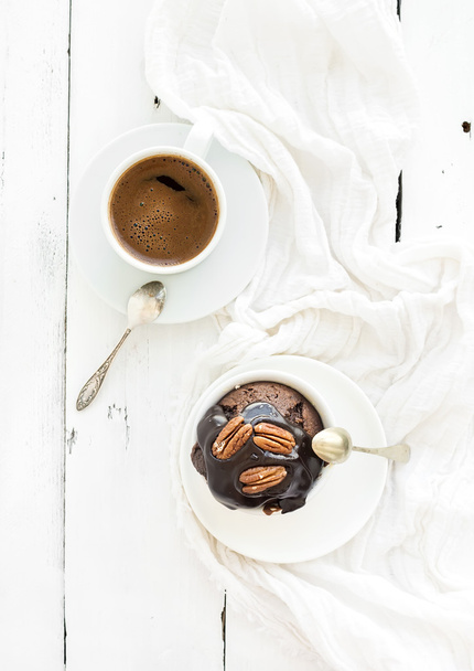 Tasty homemade brown muffin with chocolate ganache icing and pecan nuts, cup of black coffee.  - Zdjęcie, obraz
