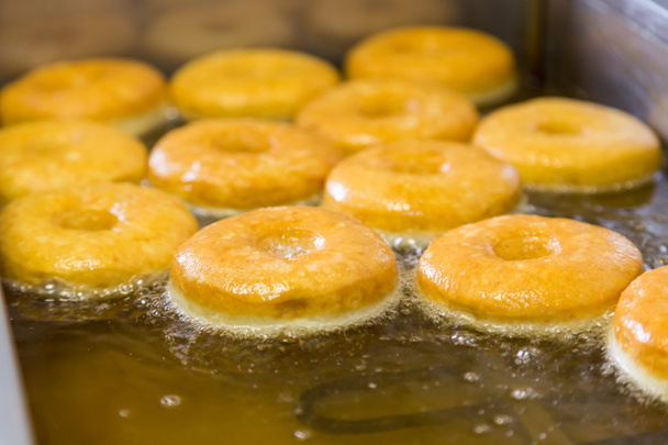 paistettuja yhtä pyöreitä donitseja uppopaistimessa
 - Valokuva, kuva