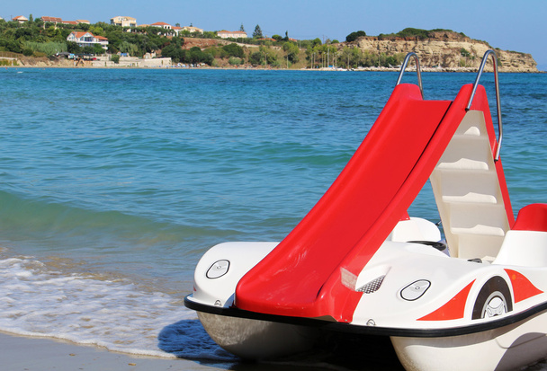 Red pedalo boat with slide on the beach - Photo, Image