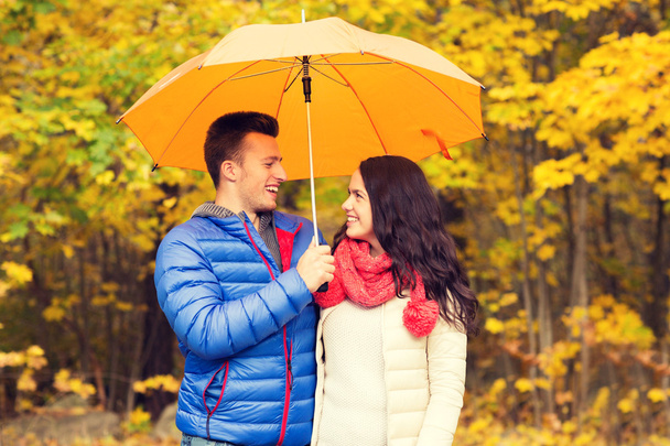 smiling couple with umbrella in autumn park - Фото, изображение