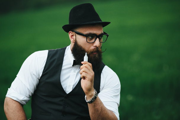 man with a beard smokes electronic cigarette - Фото, изображение