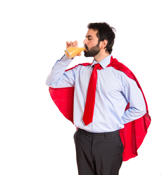 Επιχειρηματίας ντυμένος σαν υπερήρωα πίνοντας χυμό πορτοκαλιού - Φωτογραφία, εικόνα