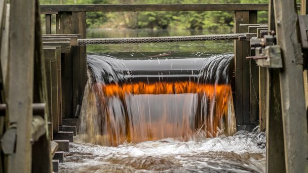 Water from a watermill near an old iron mine is colored due to the iron oxide content - Photo, Image