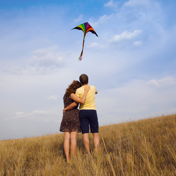 Szczęśliwa młoda para w miłości z latający latawiec na wsi - Zdjęcie, obraz