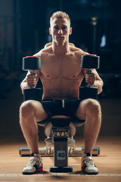 Athlete muscular bodybuilder training back with dumbbell  in the gym - Fotografie, Obrázek