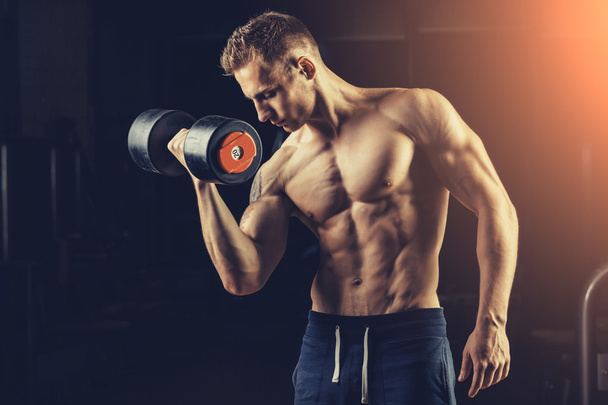 Athlete muscular bodybuilder training back with dumbbell  in the gym - Valokuva, kuva