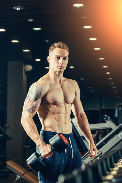 Male athlete with a dumbbell in the gym lean on row - Фото, зображення