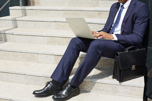 businessman typing on laptop while sitting on stairs - Valokuva, kuva