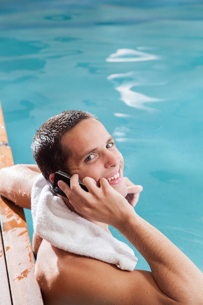 El hombre usa el celular en la piscina.
 - Foto, imagen