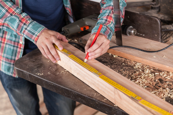 Carpinteiro medindo um pedaço de madeira
 - Foto, Imagem