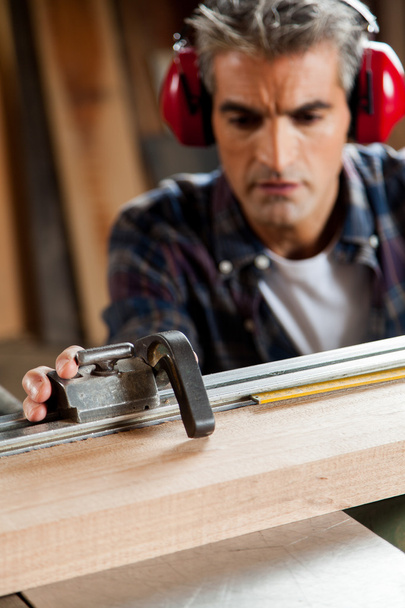 Carpinteiro medindo um pedaço de madeira
 - Foto, Imagem