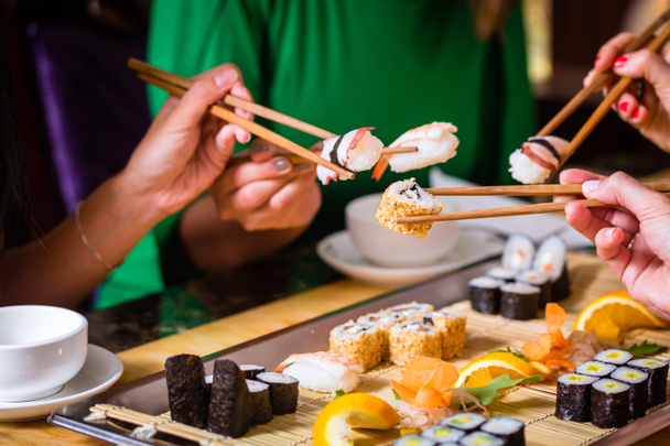 Νέους ανθρώπους που τρώνε σούσι στο ασιατικό εστιατόριο - Φωτογραφία, εικόνα