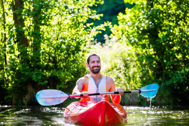 Mies melomassa kajakilla joella vesiurheilua varten
 - Valokuva, kuva
