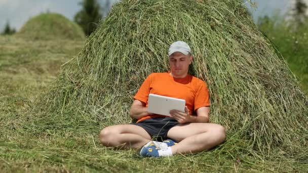 Muž s tabletovým počítačem poblíž sena - Záběry, video