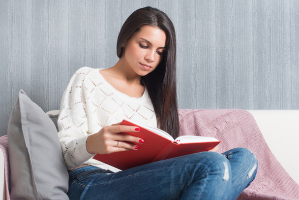 Fiatal nő ül olvas könyvet kanapé kanapé otthon  - Fotó, kép