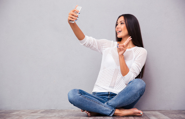 Nő ül a földön, és így selfie fénykép  - Fotó, kép