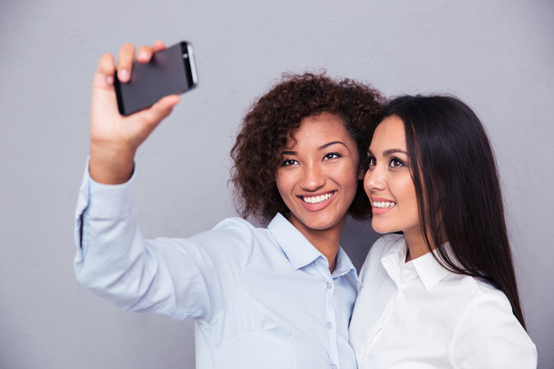 Smiling two girls making selfie photo on smartphone - Foto, imagen