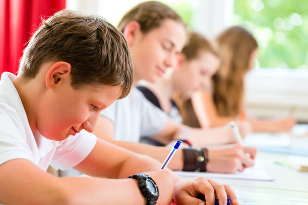 Estudantes escrevendo um teste na escola concentrando
 - Foto, Imagem