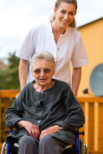 Nuori sairaanhoitaja ja nainen vanhempi pyörätuolissa
 - Valokuva, kuva