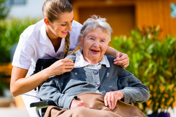 Donna anziana in casa di cura con infermiera in giardino
 - Foto, immagini